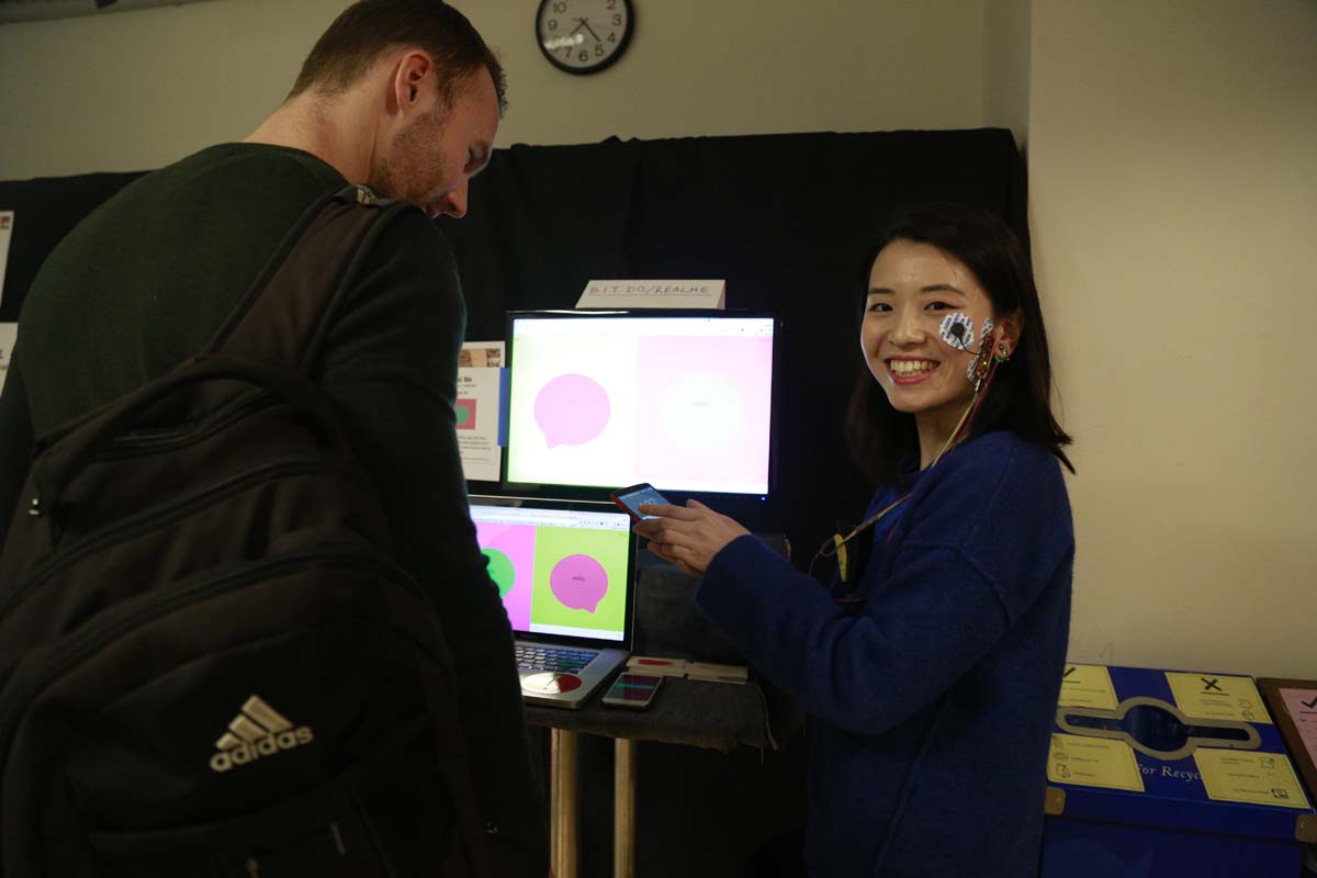 a woman smiling with a sticky sensor attached to her cheekbone