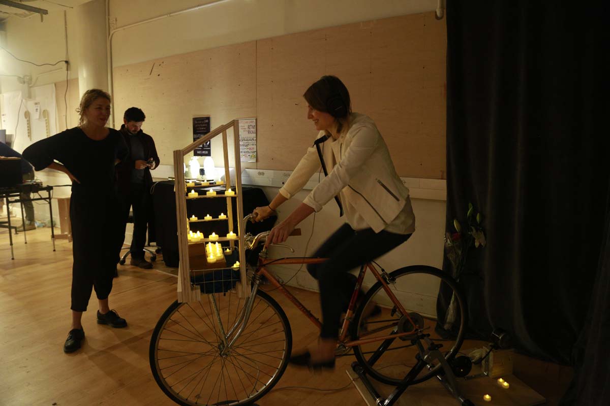 a person on a bike with a wooden structure holding tealight candles on the front of the bike