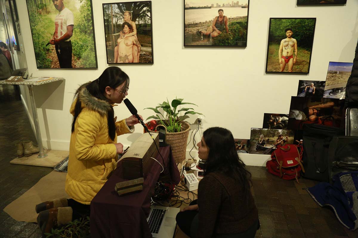 color portraits on the wall while a woman speaks into a microphone