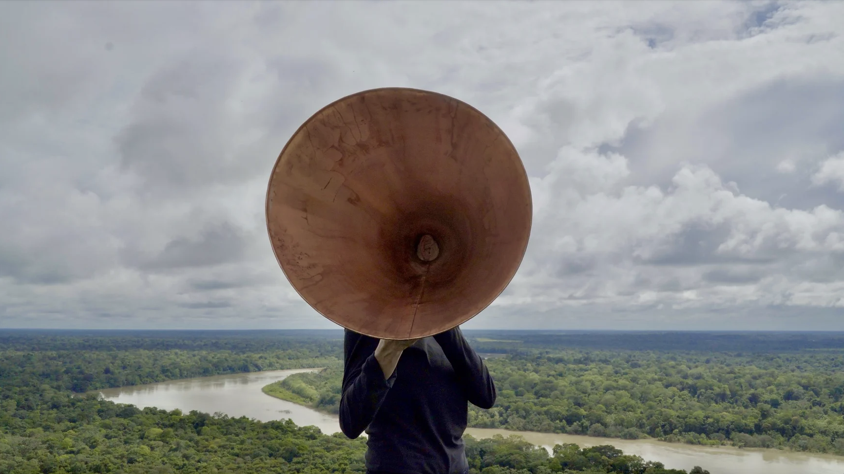 person standing with horn in front of the river 