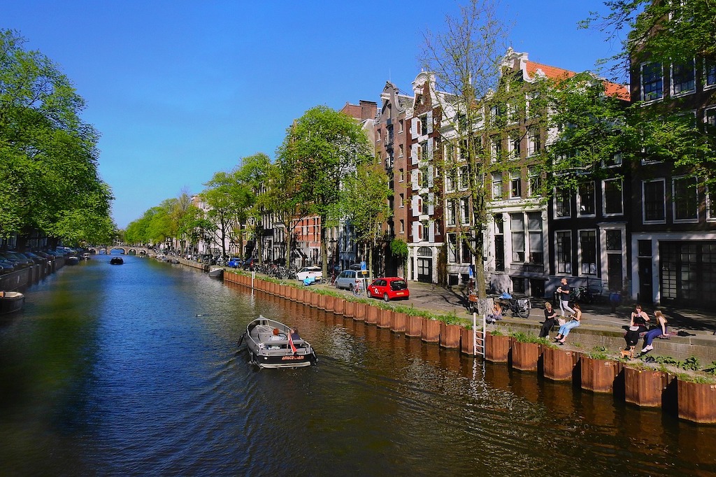 A boat drifts down a canal in Amsterdam during the day.