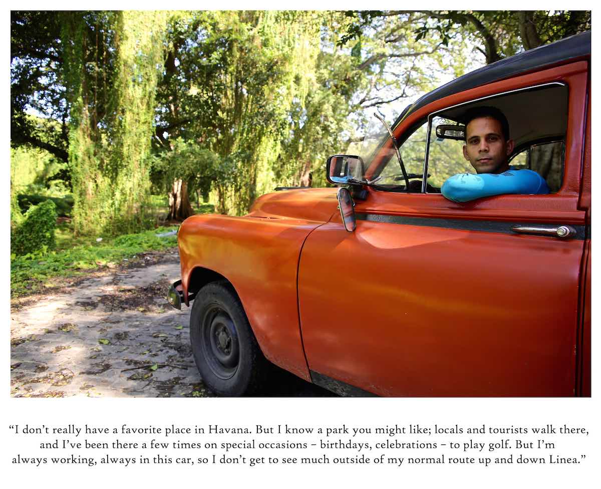 Driver hanging out the window of a vintage orange car.