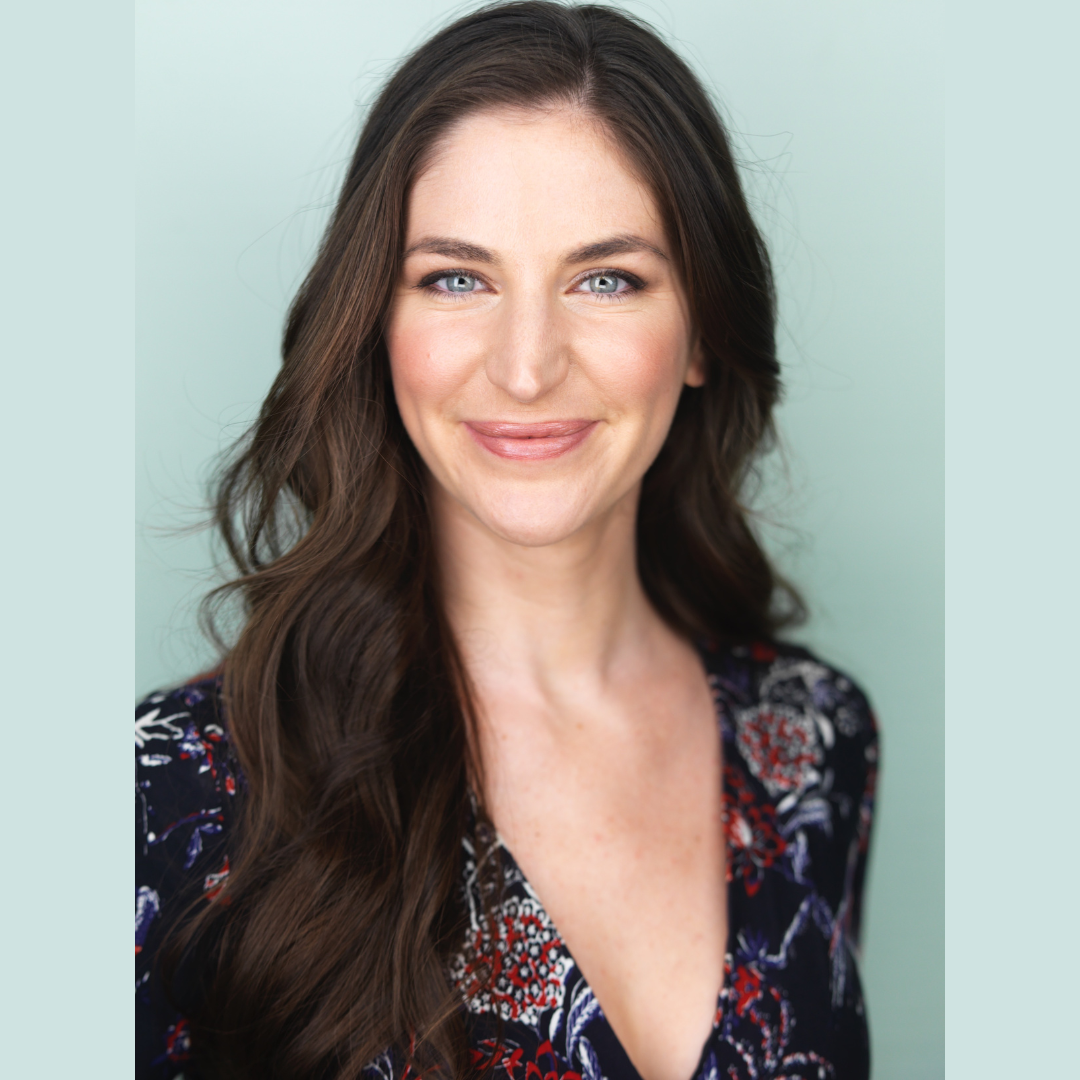 professional headshot of a smiling woman with looking into the camera with a light teal background